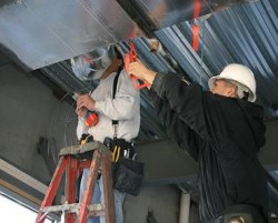 Two students working on an industrial ceiling assembly