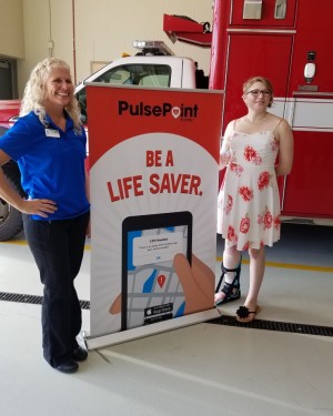 Two women stand next to a Pulse Point sign.