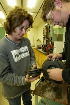 Teacher demonstrating to student at bench grinder in machine tool classroom