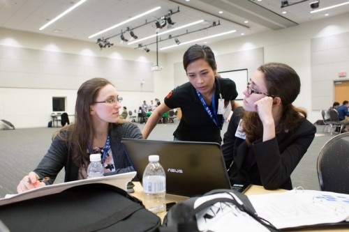 Three women look at a laptop.