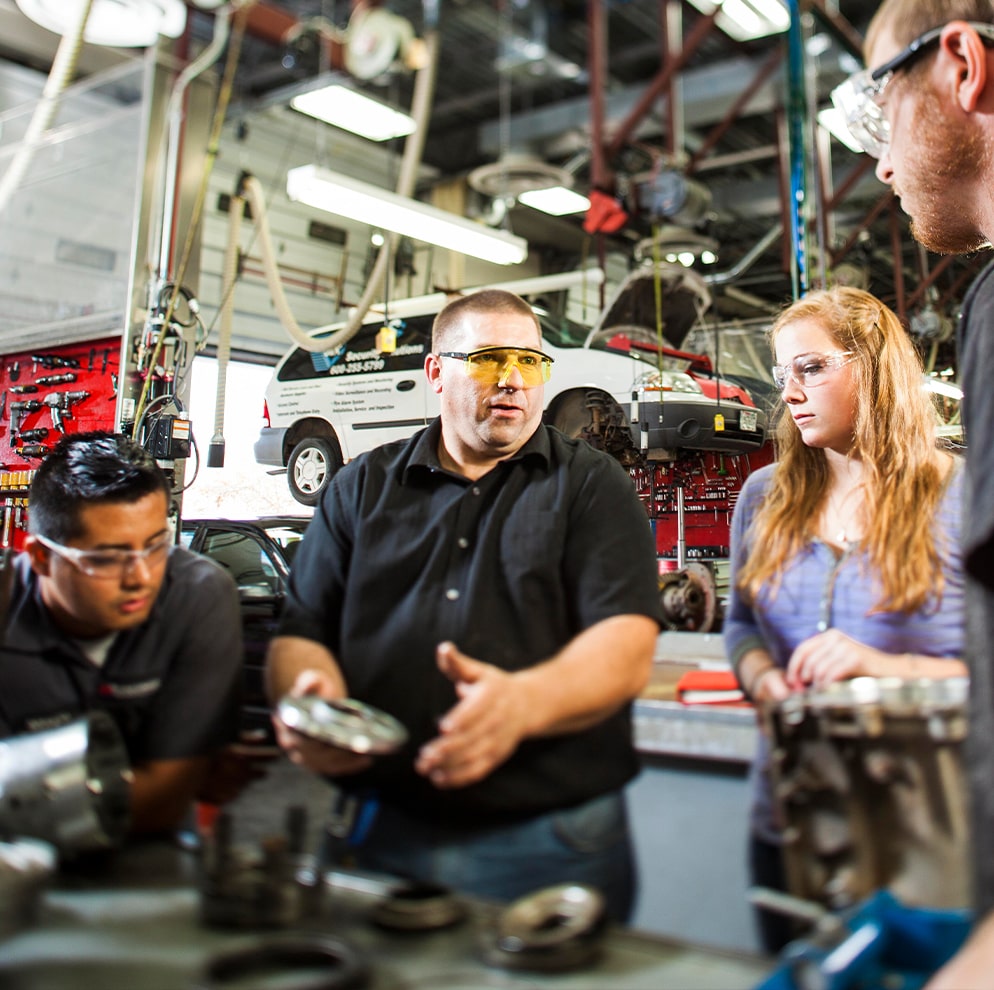 Instructor teaching to students in automotive shop