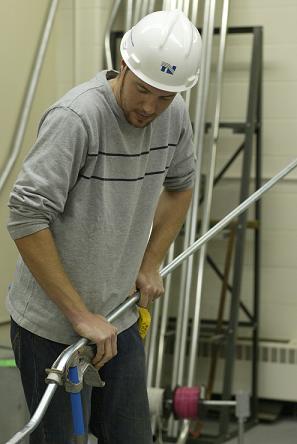 Student in an Electrician's class wearing a hard hat working with conduit