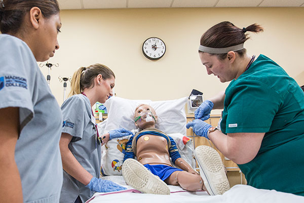 nursing students practicing with a mannequin