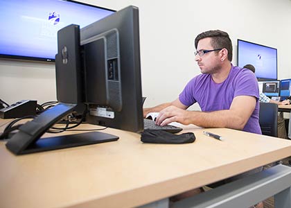 student seated at a windows work station in a classroom.