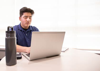 Seated student working on a windows laptop.