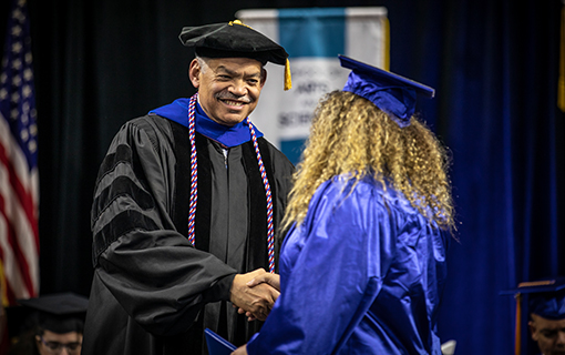 President Daniels shaking a student's hand at graduation