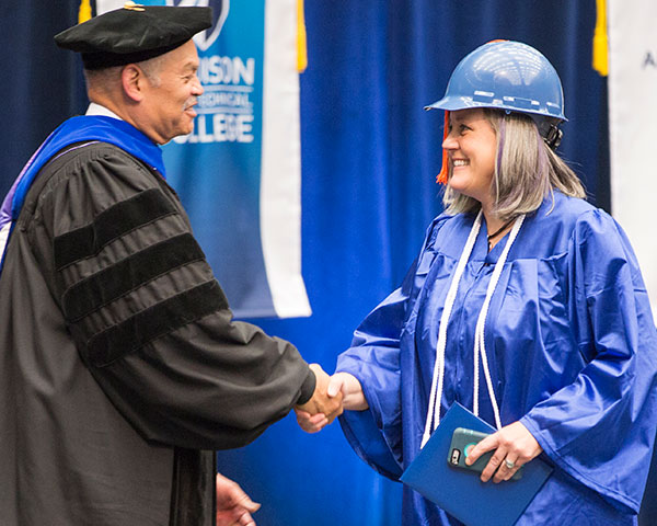 new graduate in hard hat receiving diploma