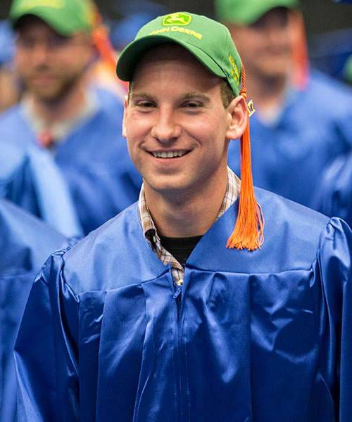 Madison College graduate wearing a cap with a brand of tractor