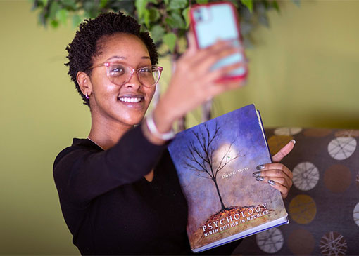 proud student takes selfie with textbook