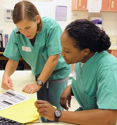 two people wearing medical scrubs reviewing a document